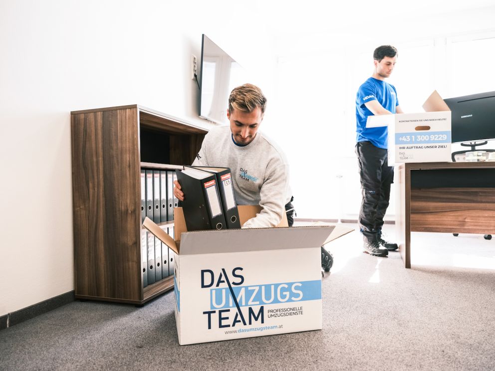 Zwei Umzugsmonteure von dem dasUmzugsteam räumen Ordner in einem Büro ein - Firmenumzug