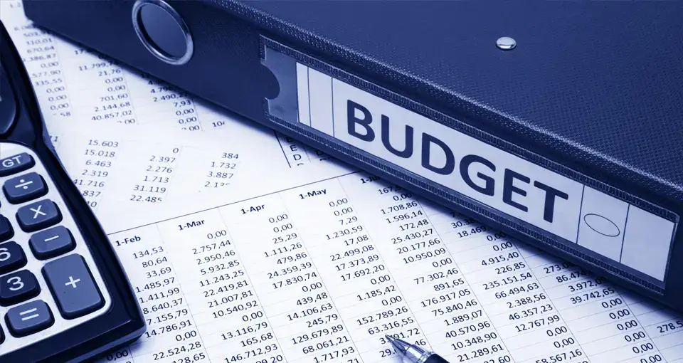 Taschenrechner, Listen und Aktenordner liegen für die Budgetplanung des Büroumzugs auf dem Tisch