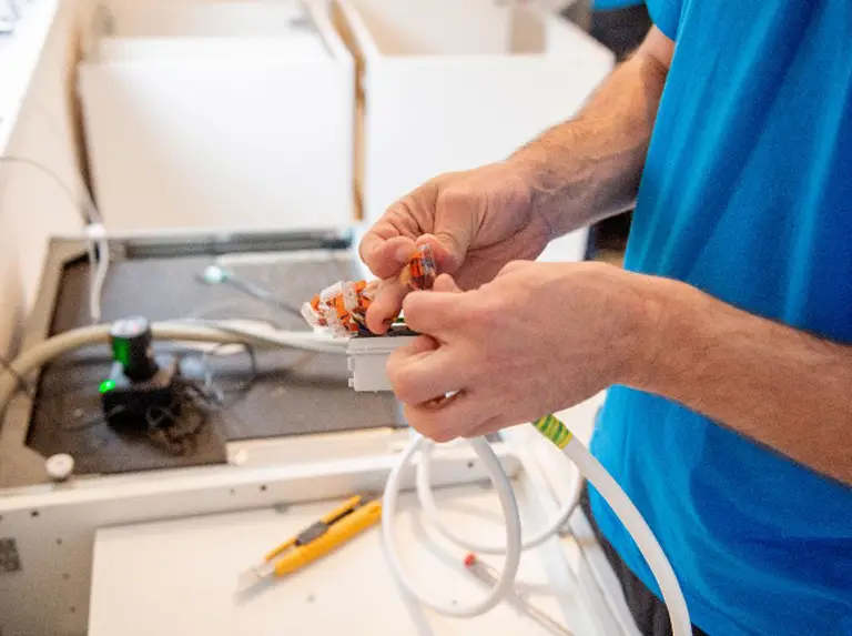 Ein Monteur vom DasUmzugsteam kümmert sich während einer Küchenübersiedlung um den Anschluss des Elektroherds.