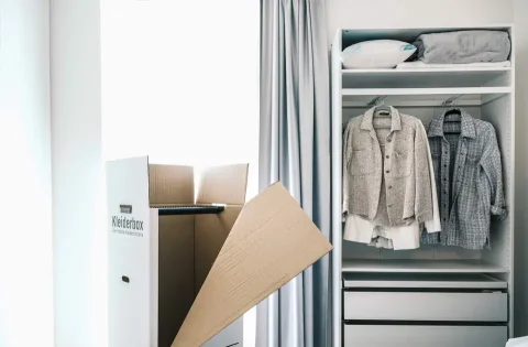 Schlafzimmers mit einem vollen Kleiderschrank und eines leeren Kleiderkarton.