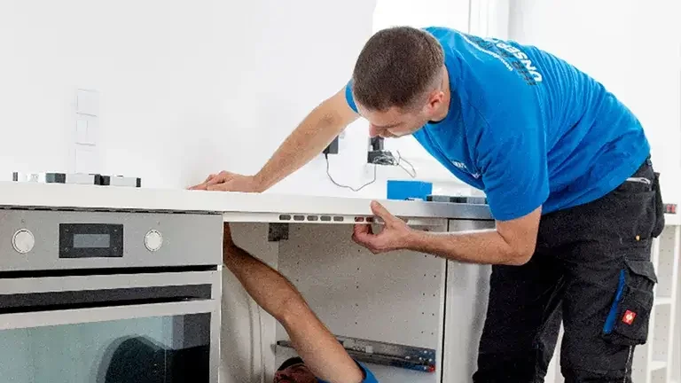 Zwei Männer montieren das Induktionsfeld in einer Küche