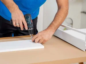Mitarbeiter von DasUmzugsteam baut ein halboffenes Bücherregal fachgerecht zusammen.