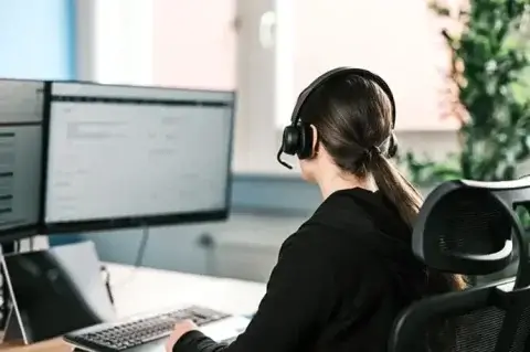 Eine Sales-Mitarbeiterin sitzt vor einem PC und bearbeitet Angebote