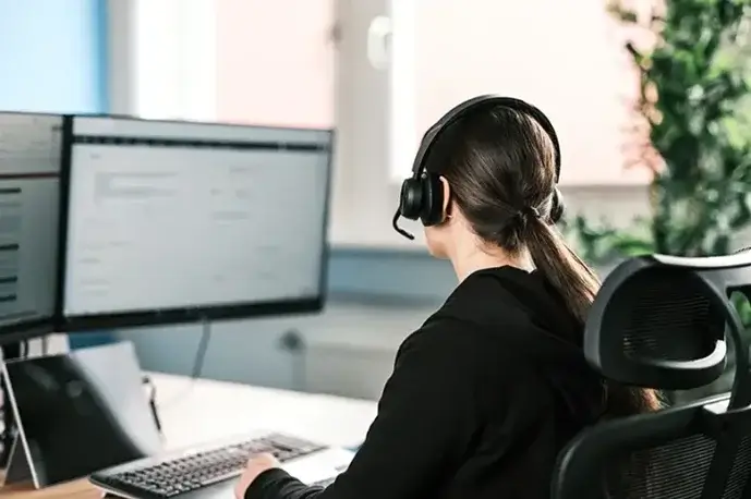 Eine Sales-Mitarbeiterin sitzt vor einem PC und bearbeitet Angebote