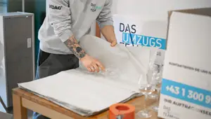 Ein Möbelpacker verpackt Gläser in Seidenpapier