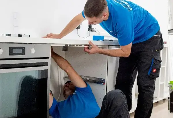 Zusatzleistungen Umzug: 2 Möbelpacker montieren eine weiße Küchenarbeitsplatte