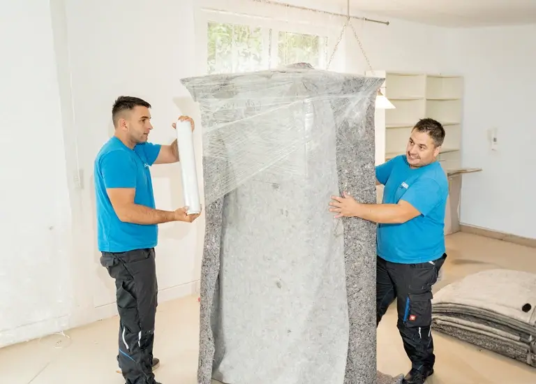 2 Möbelpacker verpacken Kasten